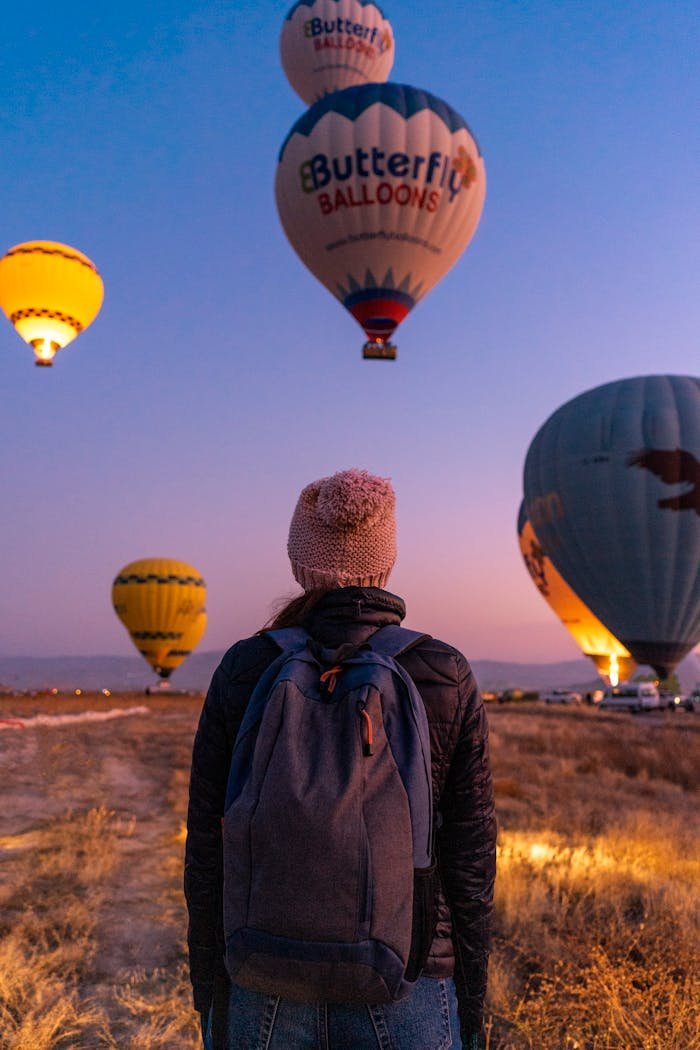 A person watches colorful hot air balloons soar during sunrise in Cappadocia, Turkey.